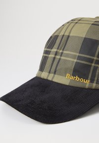 Zöld kockás sapka fekete kordbársony napellenzővel. Hímzett arany "Barbour" logóval rendelkezik. Strukturált dizájn, lapos karima és texturált anyagok jellemzik.