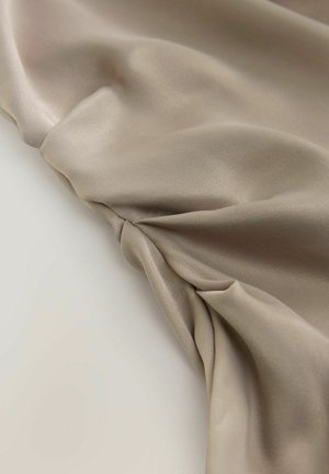 Hellbeige, glattes Gewebe mit sanftem Fall und dezentem Glanz, das an einer Kante mit Raffung strukturiert ist, um Textur und Designinteresse zu schaffen.