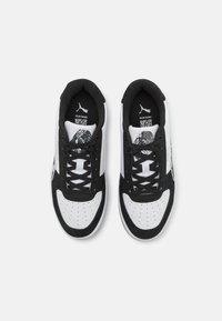 Des baskets noir et blanc présentent une tige en cuir lisse avec des accents en daim, un bout rond, un design perforé et des lacets plats.