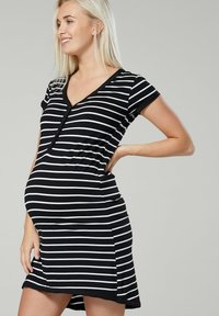 Black and white striped maternity dress with short sleeves, V-neck, and button accents, offering a fitted style and soft fabric texture.