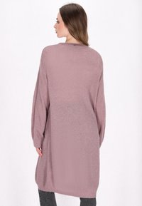Larga chaqueta de punto abierto en suave color malva, con un corte holgado, hombros caídos y puños de canalé, combinada con leggings grises.