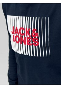 Tengerészkék, hosszú ujjú ing, fehér csíkos grafikával, amelyen a "JACK & JONES" felirat piros színben van nyomtatva az elején. Puha pamut anyagból készült.