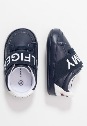 Granatowe buty dziecięce z białymi podeszwami, elastycznymi paskami z napisem "TOMMY HILFIGER" oraz miękką skórzaną konstrukcją, rozmiar 17.