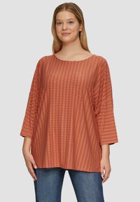 Gestreepte oversized top in roest en crème, met een bootnek en driekwartmouwen, gemaakt van lichtgewicht, gestructureerde stof.