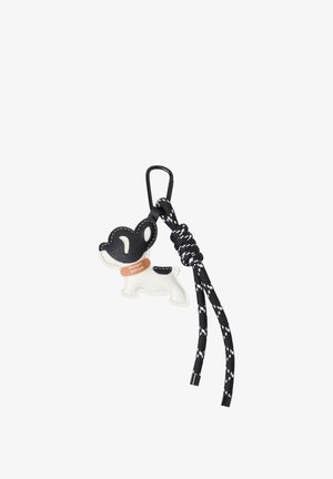 Nøglekæde med sort og hvid hundeformet vedhæng og knyttet sort snor med hvide detaljer fastgjort til en sort klemme.