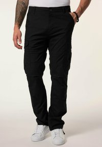 Zwarte cargobroek met meerdere zakken, een knoopsluiting en een recht model, gecombineerd met witte sneakers. Gestructureerde stof.