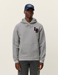 Pelēks kapuce ar vertikāliem jūras zila svītrām, priekšējo kabatu, auklu ap kaklu un izšūtu logo uz krūtīm.