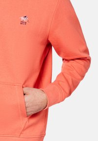 Koronkowy sweatshirt z kieszenią z przodu, ściągaczami oraz haftowanym logo. Miękka faktura i klasyczny krój.