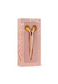 Rouge doré rouleau facial avec des embouts en pierre jaune, emballé dans une boîte rose avec des accents géométriques et le nom de marque "CRYSTALLOVE."