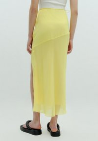 Geel doorzichtig maxi-rok met een zijsplit, voorzien van een lichte, vloeiende stof, een strikband en een gelaagd ontwerp.