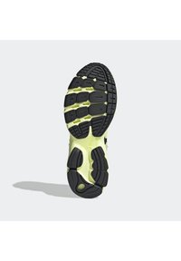 Suola della scarpa con un motivo in gomma nera, caratterizzata da accenti gialli. Superficie testurizzata con scanalature per aderenza e stabilità.