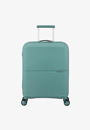 Una valigia rigida color turchese con una texture a strisce diagonali, una maniglia telescopica e quattro ruote girevoli per una facile manovrabilità.