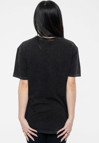 Black cotton oversized t-shirt with short sleeves, a crew neck, and subtle texture. No visible patterns or hardware.
