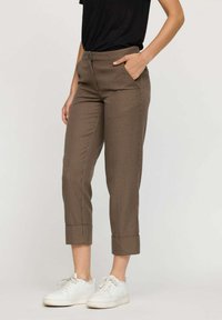 Pantalons raccourcis à carreaux marron avec une coupe droite, des poches avant et des ourlets retroussés, associés à des baskets blanches à tige basse.