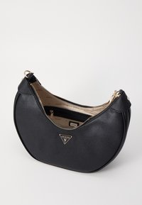 Borsa a mano in pelle nera con forma curva, hardware dorato e chiusura con zip. L'interno presenta una fodera beige con il logo del marchio ripetuto.