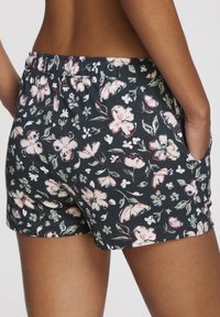 Bloemenprint shorts in donkerblauw, gemaakt van zachte stof met een elastische tailleband en zijzakken. Heeft roze en groene bloemenaccenten.