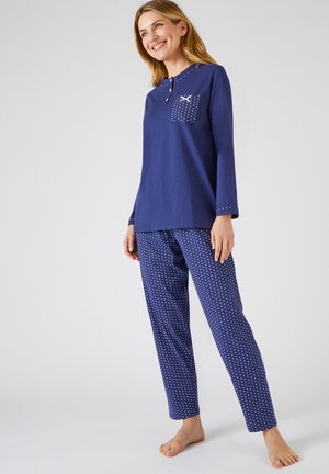Set di pigiama blu navy composto da una maglietta a maniche lunghe con taschino e piccoli dettagli a pois, abbinata a pantaloni a pois. Realizzato in morbido cotone.