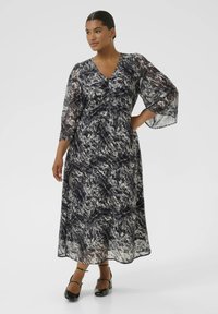 Robe maxi en tissu transparent avec un motif en noir, blanc et gris tourbillonnant. Dotée d'un décolleté en V et de manches cloche trois-quarts.