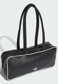 Czarna skórzana torba typu tote z białym obszyciem, zamkiem błyskawicznym i podwójnymi uchwytami. Na przodzie znajduje się małe białe logo. Prostokątny kształt.
