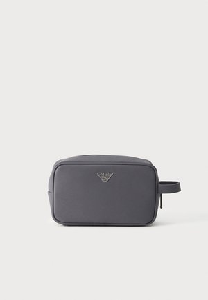 Trousse de toilette rectangulaire gris foncé avec logo argenté centré sur le devant et une poignée latérale à droite.