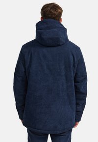 Navyblaue Cordjacke mit großer Kapuze und strukturierter Oberfläche, relaxter Passform und langen Ärmeln.