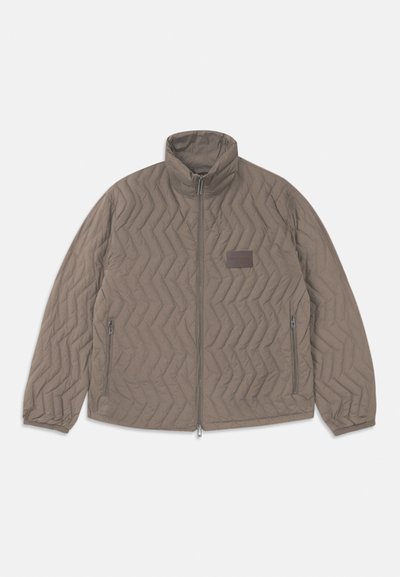 Rudens brūns, adatots jaku ar augstu apkakli, ar rāvējslēdzēju priekšpusē un divām sānu kabatām. Iezīme diagonālas zigzaga raksts un neliela auduma etiķete.