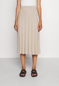 Beige, plissierter Midirock aus einem weichen, strukturierten Stoff. Verfügt über einen taillierten Bund und reicht bis unter das Knie. Kombiniert mit schwarzen Sandalen.
