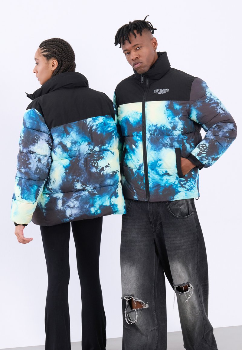Pufferjack met een zwarte bovenkant en een kleurrijk patroon in blauw, groen en wit op de onderste sectie. Rits sluiting en zijzakken. Casual fit.