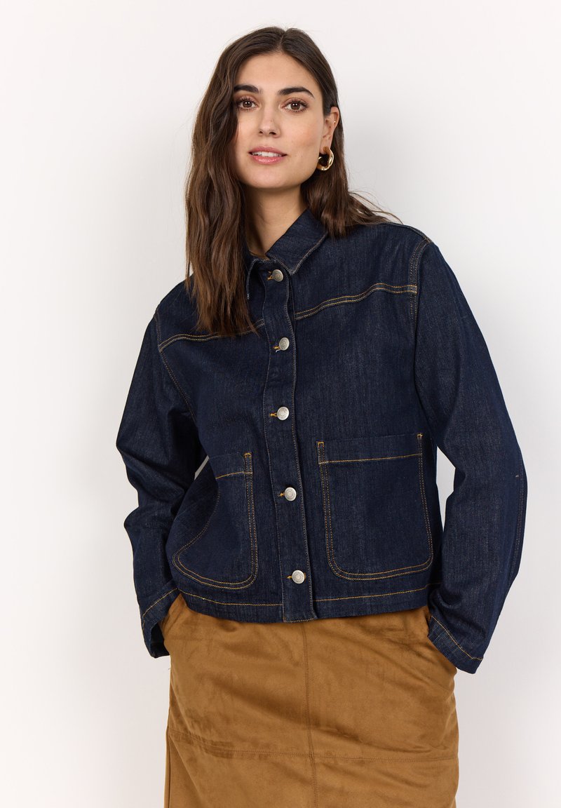 Mörkblå denimjacka med krage, knappfront och två stora framfickor. Har kontrasterande gula sömmar och en avslappnad passform.