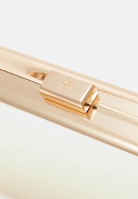 Prostokątna metalowa kopertówka w złotym odcieniu z wyraźnym zapięciem ozdobionym logo. Gładka powierzchnia o refleksyjnym wykończeniu. Bez widocznych wzorów.