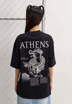 Schwarzes übergroßes T-Shirt mit weißem Grafikdruck einer griechischen Statue und Text; kurze Ärmel, Rundhalsausschnitt und lockere Passform.