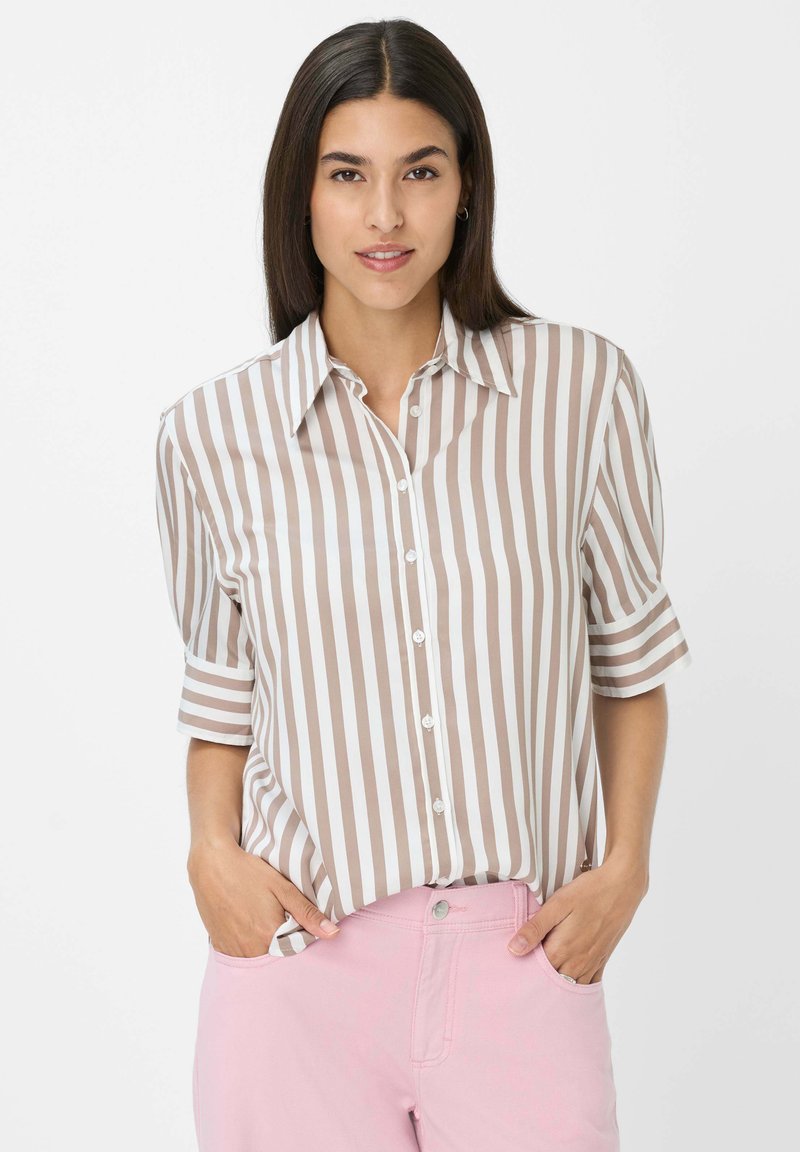 Chemise rayée marron et blanche avec un devant boutonné, des manches courtes et un col classique. Texture de tissu lisse. Un pantalon rose est visible.