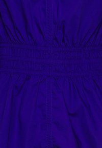 La vita elastica viola con tessuto arricciato crea un aspetto testurizzato e vaporoso, caratterizzato da materiale leggero e liscio e dettagli di cucitura sottili.