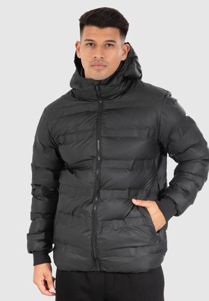 Doudoune noire rembourrée avec fermeture éclair sur le devant, col montant et capuche. Présente une couture horizontale et des poignets élastiques, fabriquée dans un matériau lisse et léger.
