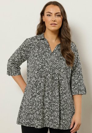 Black and white printed tunic with a collared neckline, three-quarter sleeves, and a flared silhouette. Lightweight fabric with a textured pattern.
