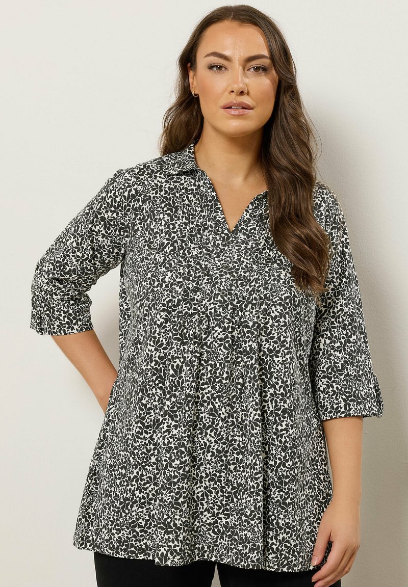 Tunic stampata in bianco e nero con scollatura a colletto, maniche a tre quarti e silhouette svasata. Tessuto leggero con un motivo testurizzato.