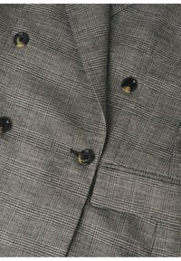 Dwurzędowa marynarka w szarym wzorze w kratę, z czarnymi guzikami, ostrym kołnierzem i teksturowaną tkaniną dla dopasowanego wyglądu.