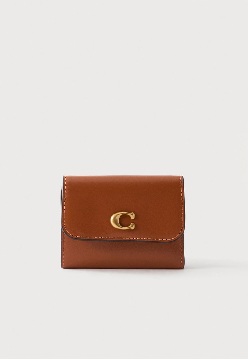 Petit portefeuille en cuir marron avec un emblème en métal doré « C » sur le rabat avant, présenté sur un fond uni clair.