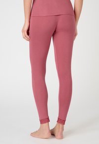 Leggings rosa realizzati in un morbido tessuto, design aderente, con dettagli in pizzo ai polsini. Tessura liscia, leggeri e con una vestibilità flessibile.