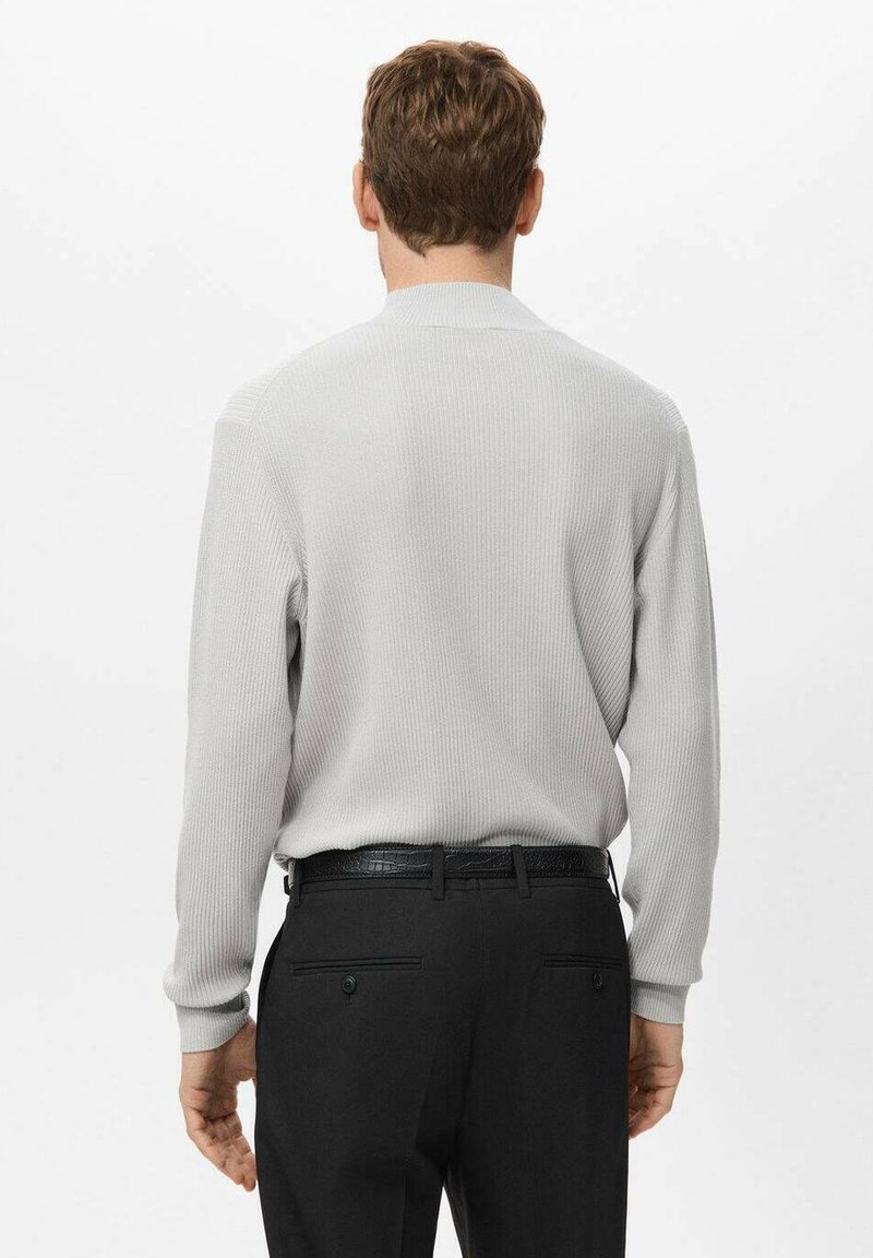 Light grey ribbed sweater with a high collar, paired with black dress pants and a textured belt. The sweater features long sleeves.