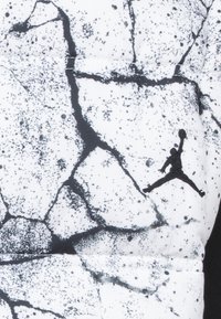 Sort-hvidt mønstret stof med et sprucket design og prikker. Indeholder en sort Jordan-logo silhuet i hjørnet.