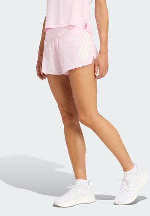 Light pink running shorts with a relaxed fit, featuring white side slits and three white stripes on the right side, paired with white sneakers.