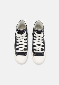 Wysokie trampki w granatowym płótnie z białymi sznurowadłami, gumowym noskiem i szytymi detalami. Posiadają boczny zamek błyskawiczny ułatwiający zakładanie.