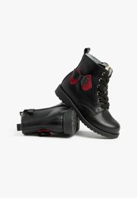 Schwarze Leder-Ankle-Boots mit roten Glitzer-Schleifenakzenten, Schnürvorderseite und seitlichen Reißverschlüssen. Strukturierten Gummisohlen für besseren Halt.