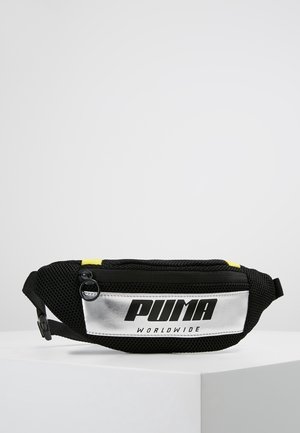 Sort mesh Puma bæltetaske med sølv frontpanel, sort lynlås og "PUMA WORLDWIDE" logo i fede sorte bogstaver.
