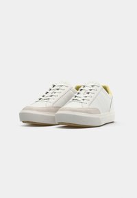 Sneakers bianchi in pelle con punta in suede, dettagli perforati, lacci piatti e fodera gialla a contrasto. Suola in gomma spessa.