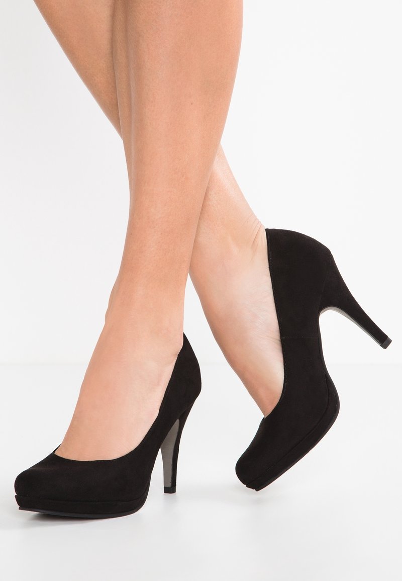 Escarpins en daim noir avec un bout rond, une texture lisse et un talon fin. Le design présente une légère plateforme à l'avant.