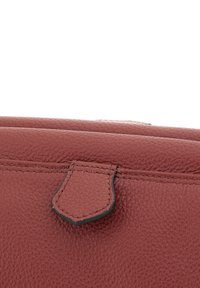 Borsa a tracolla in pelle rossa con una texture a granuli, caratterizzata da una parte superiore cucita e una chiusura con linguetta distintiva. Design minimalista senza loghi visibili.