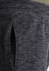 Dark grey athletic pants made of soft, textured fabric. Features a side pocket and a smooth waistband.