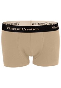Caleçons beiges avec une ceinture élastique noire griffée portant "Vincent Creation" en lettres dorées. Tissu doux et coupe ajustée.
